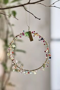 an ornament hanging from a tree branch with beads and charms on it's end