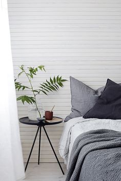 a bed sitting next to a table with a potted plant on it