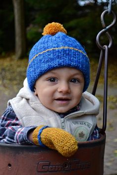 a small child wearing a blue hat and holding onto a swing