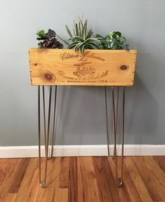 a wooden planter with plants in it sitting on top of a wood floor next to a wall