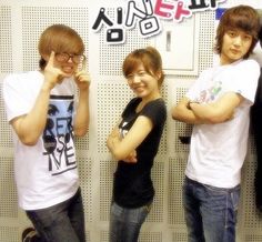 three young men standing next to each other in front of a wall with writing on it