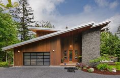 a modern house in the woods with stone and wood accents