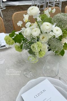 the table is set with white flowers and greenery