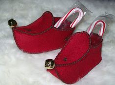 two red slippers with candy canes in them on a white fur surface,