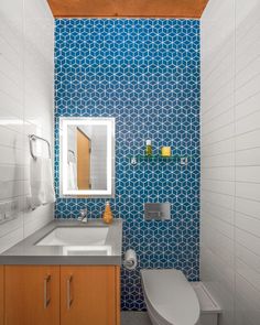 a bathroom with blue and white tiles on the wall, toilet, sink and mirror