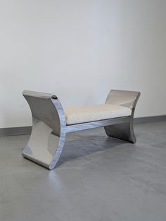 a white bench sitting on top of a cement floor next to a wall in an empty room