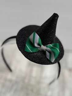 This little witch hat fascinator is perfect for Halloween! Hat is attached to a plastic headband covered with black silky material. Headband is soft and flexible, which makes for a comfortable fit. It is a standard size headband, which will fit both adults and older children. Witch hat is made of glitter foam and is attached to the headband, but is able to slide on the headband so you can wear the hat on the top of your head or on either side. Hat is adorned with a green and silver ribbon bow th Green And Silver Hair, Material Headband, Witch Hat Headband, Wizard Cosplay, Silver Hair Accessories, Halloween Hat, Hat Headband, Hat Fascinator, Plastic Headband