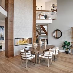 a dining room table with white chairs next to a fire place