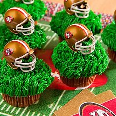 some cupcakes with football helmets on top of them are sitting on a table