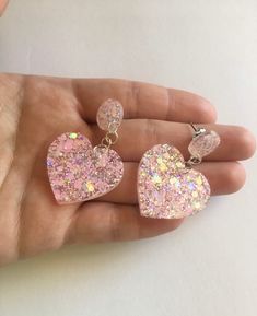 Each pair of pink resin heart earrings are handmade to order, therefore no two pairs are identical! Every jewelry piece is slightly unique and one of a kind! However, I try to get as close to the photos as possible :) Made with non-toxic stainless steel stud earrings. Nickel-free & hypoallergenic.  Hearts are approximately 1.25", and are made with epoxy resin, pastel pink iridescent glitter, and white chunky holographic glitter ✨  These dangle drop heart earrings are perfect for Valentine's Day, Resin Studs Earrings, Pink Kawaii Jewelry For Valentine's Day, Kawaii Pink Jewelry For Valentine's Day, Resin Heart Earrings, Pink Heart-shaped Kawaii Jewelry, Pink Kawaii Heart-shaped Jewelry, Pink Heart Cut Earrings For Party, Pink Glitter Drop Earrings, Cute Pink Double Heart Jewelry