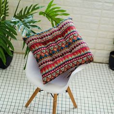 a pillow sitting on top of a white chair next to a potted green plant