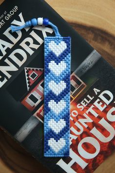 a bookmark made out of seed beads on top of a wooden table next to a magazine