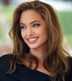 a woman with long brown hair and blue eyes smiles at the camera while wearing a black top