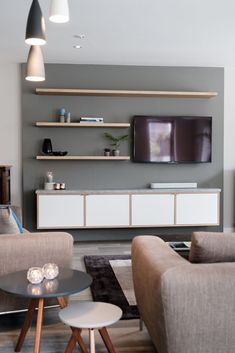 a living room with two couches and a flat screen tv mounted on the wall