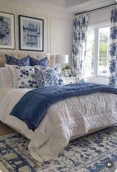 a bed with blue and white comforters in a bedroom next to a large window