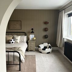 a bed room with a neatly made bed and a soccer ball pillow on the floor