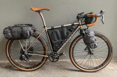 a bicycle parked next to a wall with a bag on it's front rack