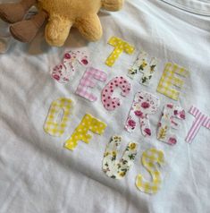 a teddy bear sitting on top of a white t - shirt