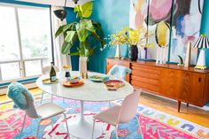 a dining room with blue walls, white chairs and a round table in the center