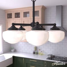 three lights are hanging from the ceiling in a kitchen with green cabinets and white counter tops