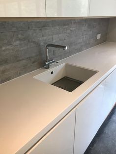 a white kitchen sink sitting under a faucet on top of a countertop