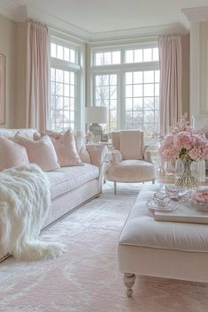 a living room filled with lots of furniture and pink flowers on top of a table