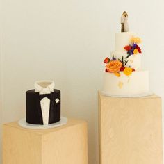 two wedding cakes sitting on top of wooden blocks next to each other in front of a white wall