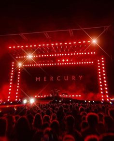 a large group of people standing on top of a stage with lights in front of them