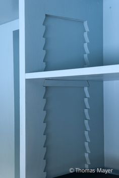 an empty shelf in a room with blue walls and white shelving unit dividers