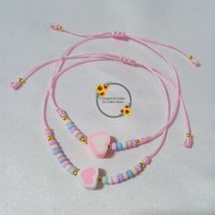 two necklaces with hearts and beads on a white tablecloth, one has a flower in the middle