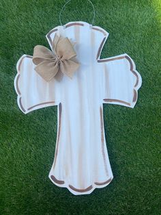 a wooden cross with a bow hanging on the grass