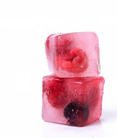 two cubes of ice with raspberries and blackberries on top, sitting next to each other