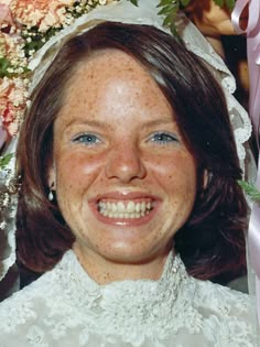 a woman with freckles on her face wearing a white dress and flower crown