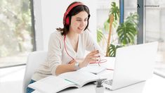 a woman sitting at a table with a laptop and headphones on