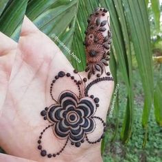 a hand with a hendi design on it and some leaves in the background,