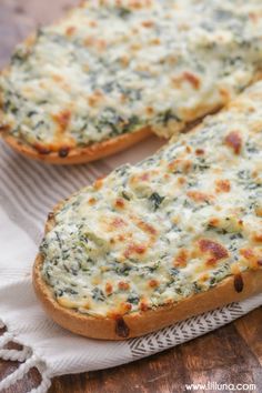 two pieces of bread with cheese and spinach on it sitting on a table next to a napkin