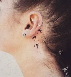 a woman's ear with birds and stars on the back of her left ear