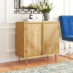 a blue chair sitting next to a wooden cabinet in a living room with white walls