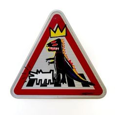 a red and white triangular sign with a dinosaur on it's face, in front of a cityscape