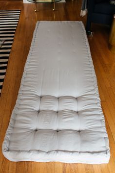 a mattress is laying on the floor in front of a black and white striped rug