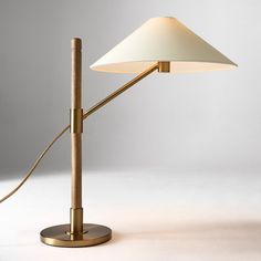 a table lamp with a white shade on it's side and a gold base