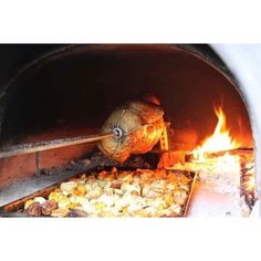 an open brick oven with food cooking in it and flames coming out from the inside