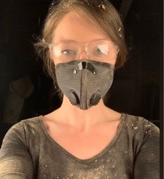 a woman wearing a mask and glasses in front of her face with dirt on it