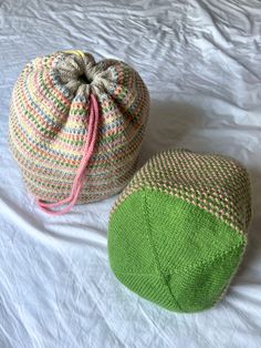 two knitted beanies sitting on top of a white bed next to each other