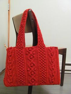 a red knitted bag sitting on top of a wooden chair