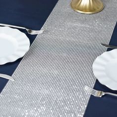 the table is set with white plates and silver cutlery, along with blue napkins