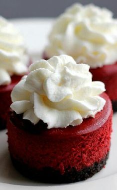 two red velvet cakes topped with whipped cream on top of each other, sitting on a white plate