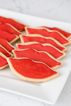 some cookies with red icing are on a white plate