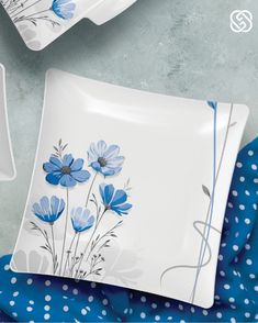 two plates with blue flowers on them sitting next to polka dot napkins and cups