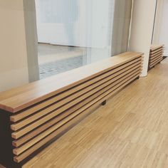 a wooden bench sitting in front of a window on top of a hard wood floor